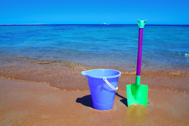 Balde azul e pá crianças férias brinquedos na praia