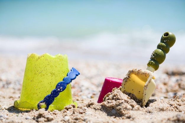 Balde de areia e brinquedos de colher na praia