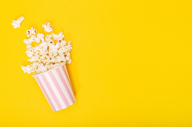 Foto balde de pipoca em fundo amarelo. fundo de filme ou tv. vista superior espaço de cópia