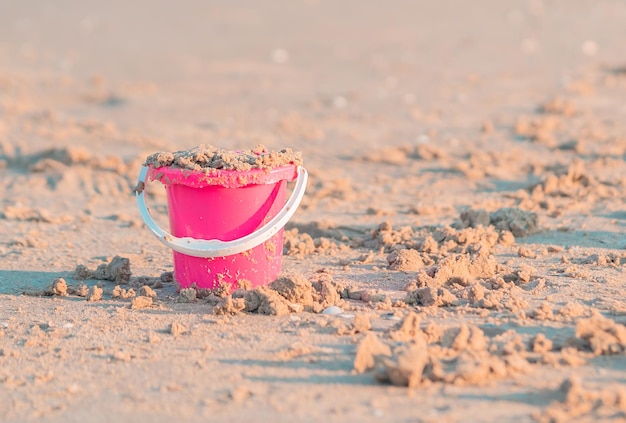 Balde de plástico rosa colorido cheio de areia para o conceito de brinquedo de férias de verão infantil