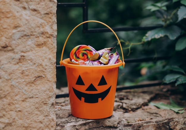 Balde laranja Halloween Jack o Lantern com doces e guloseimas ao ar livre