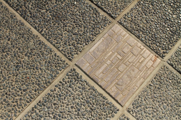 Una baldosa de textura cerámica entre las baldosas de piso de piedra de guijarros