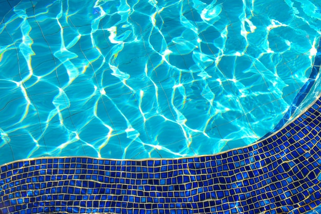 Baldosas azules de jacuzzi en el agua azul de la piscina y efecto de reflejo de la luz del sol