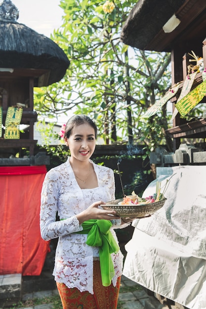 Foto bali mulher vestindo roupas tradicionais, trazendo sang canang