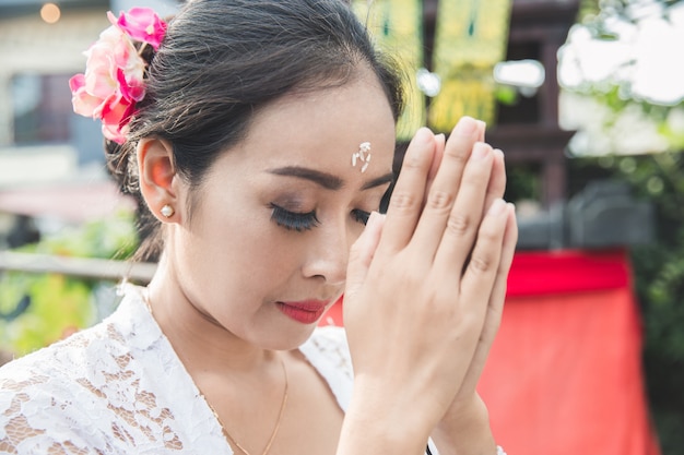 Balinesische Frau, die Tempel auf kleinen Schreinen in Häusern betet