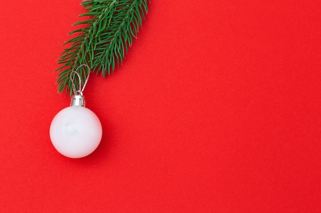 Ball der weißen Weihnacht auf Weihnachtsbaumast über rotem Hintergrund
