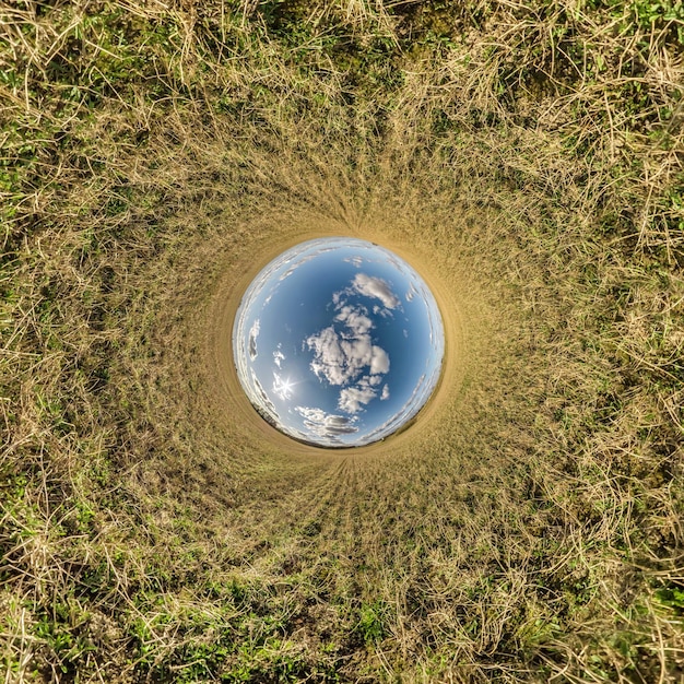 Ball des blauen Himmels in der Mitte des wirbelnden Feldes Umkehrung des winzigen Planeten Transformation des sphärischen Panoramas 360 Grad Krümmung des Raums