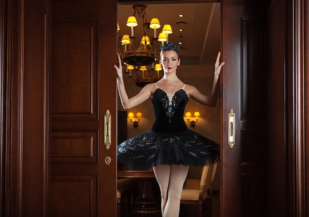 Foto ballerina im schwarzen tutu, das in der tür im luxusinnenraum steht