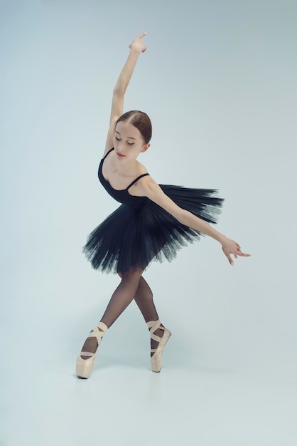 Ballerina in einem schwarzen Tutu zeigt Elemente des Balletttanzes in Bewegung