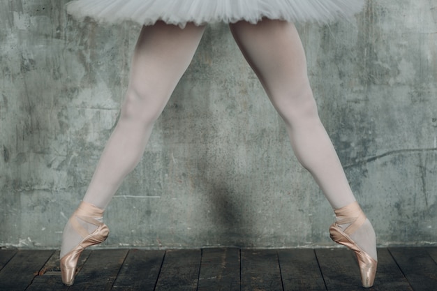 Ballerina schöne Beine. Junge schöne Frau Balletttänzerin, gekleidet in professionelles Outfit, Spitzenschuhe und weißes Tutu.