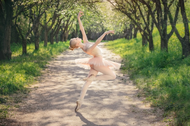 Ballerina tanzt im Freien klassisches Ballett wirft in der grünen Landschaft auf