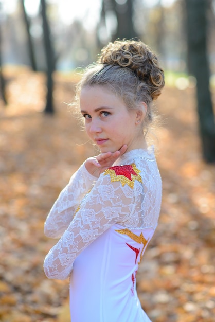 Ballerina tanzt im Naturpark unter Herbstlaub.