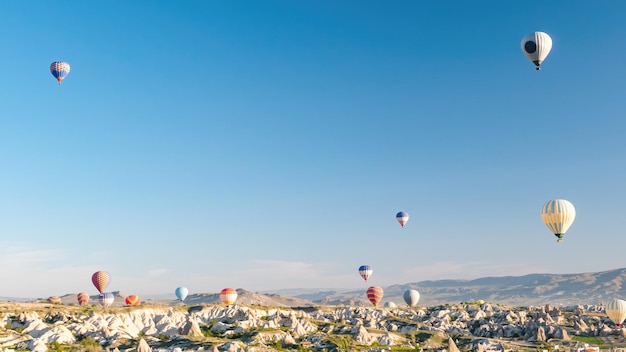 Balões de ar quente coloridos voando sobre a paisagem rochosa na Capadócia Turquia