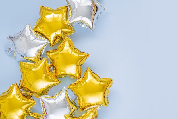Balões de folha de ouro e prata de estrela em forma de fundo azul. Conceito de férias e celebração. Dia de aniversário ou decoração de festa. Balões de ar metálicos. Parabéns. Cartão de felicitações.