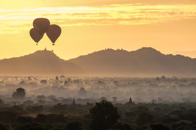 Balões voaram sobre os pagodes na névoa da manhã em Bagan Mianmar, dezembro de 2016