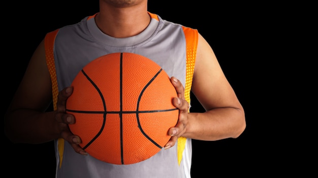 Balón de baloncesto y jugador de baloncesto aislado sobre fondo negro, primer plano