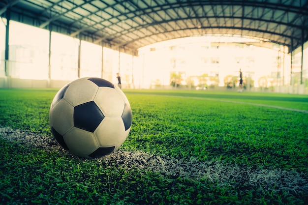 Balón de fútbol acostado en una línea divisoria blanca en un campo de fútbol.