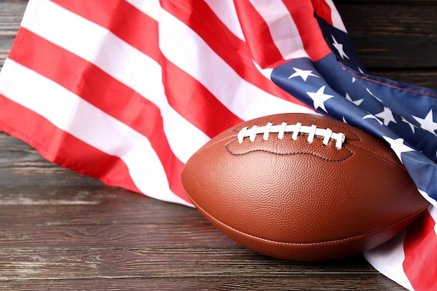Balón de fútbol americano y bandera americana sobre fondo de madera