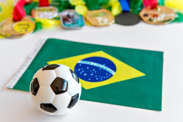 Balón de fútbol bandera brasileña y medallas sobre fondo blanco.