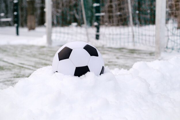 Balón de fútbol cerca de la portería de fútbol en invierno