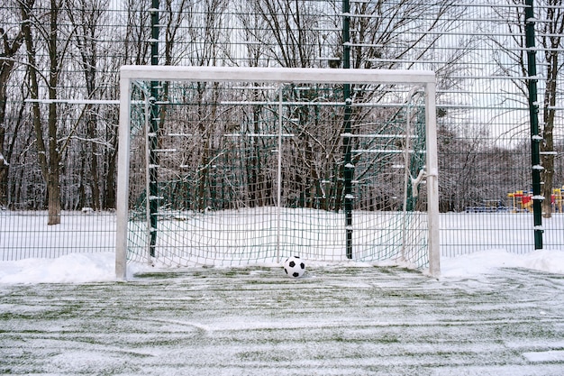 Balón de fútbol cerca de la portería de fútbol en invierno