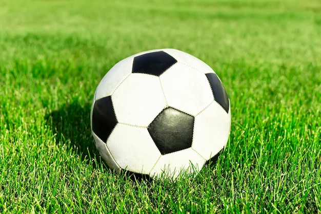 Balón de fútbol clásico patrón típico en blanco y negro colocado en el lugar del césped del estadio Balón de fútbol tradicional en el campo de hierba verde de la arena