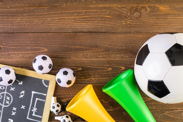 Balón de fútbol y cuernos del estadio Vuvuzela sobre un fondo de madera.