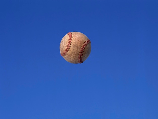 Un balón de fútbol disparado en el aire con fondo de cielo azul