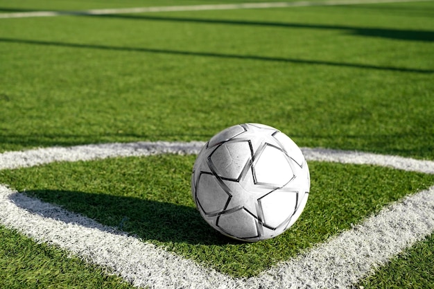 Balón de fútbol en la esquina del campo de césped artificial