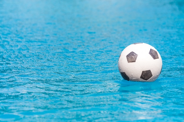 Foto balón de fútbol flotando en la piscina