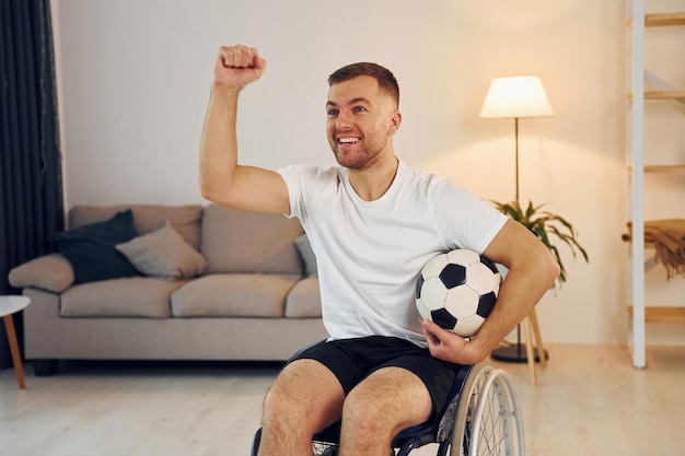 Foto con balón de fútbol hombre discapacitado en silla de ruedas está en casa