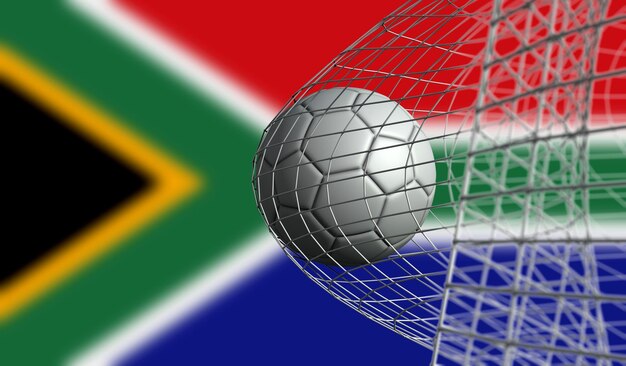 El balón de fútbol marca un gol en una red contra la representación 3D de la bandera de Sudáfrica