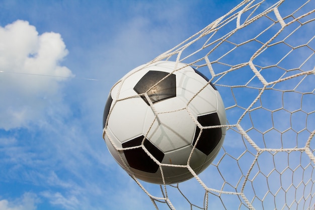 Foto balón de fútbol en la meta en el cielo de nubes