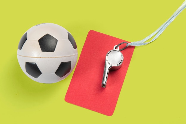 Foto balón de fútbol, tarjetas amarillas y rojas y silbato de árbitro.