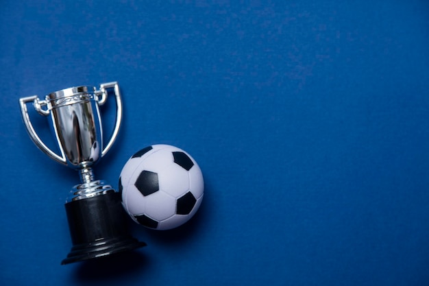 Foto balón de fútbol con un trofeo ganador de plata