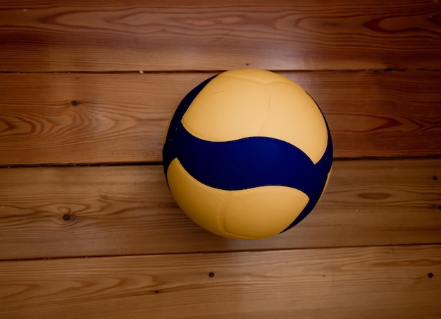 Balón de voleibol azul amarillo se encuentra en un piso deportivo de madera espacio libre juego activo aislado