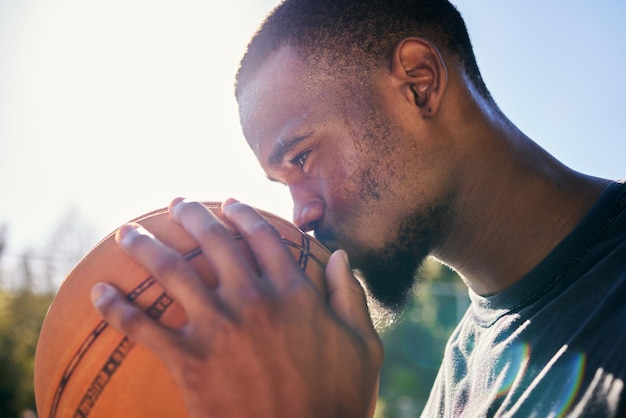 Baloncesto de hombre negro y beso por deportes amor pasión o dedicación en motivación buena suerte o elogios en la cancha Jugador de baloncesto masculino afroamericano besando la pelota de la suerte por puntuación o punto