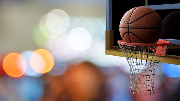 Baloncesto que entra en el aro en el hermoso bokeh de fondo claro colorido estadio