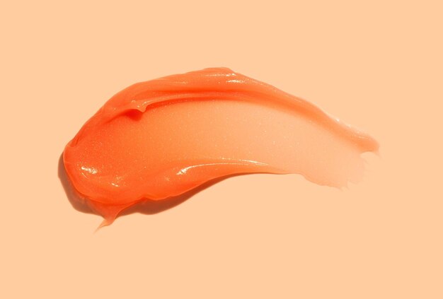 Bálsamo labial para el cuerpo o el cabello máscara de mantequilla textura de color naranja muestra de mancha sobre fondo beige