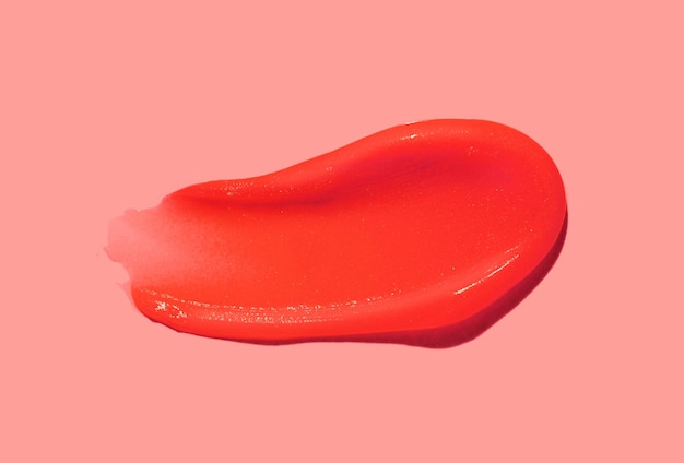 Bálsamo para los labios en tono rojo naranja de textura de color muestra de mancha en el fondo