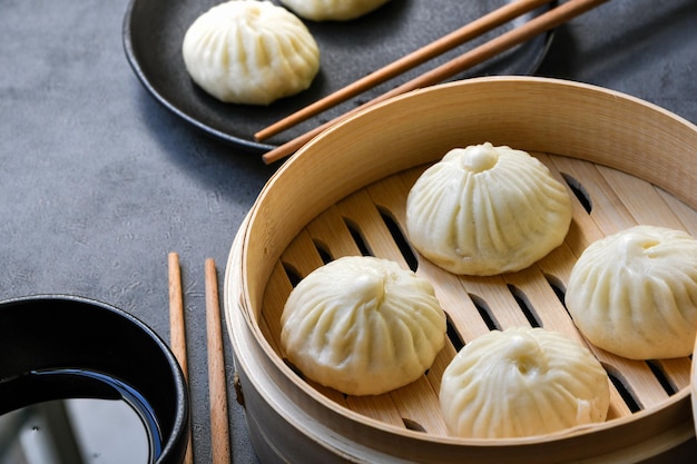 Foto bambusdampfer mit leckeren baozi-knödeln, essstäbchen und saucenschüssel