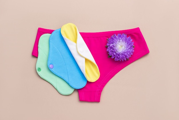 Bambuskohle waschbare Damenbinden Eco wiederverwendbare Menstruationspads und Unterhosen auf beigem Hintergrund Frauengesundheitskonzept umweltfreundliche Null-Abfall-Alternativen