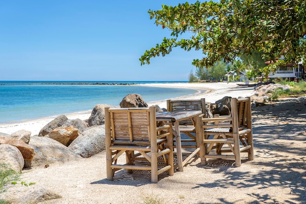 Bambustisch und Stühle am tropischen Sandstrand in der Nähe des blauen Meerwassers auf der Insel Koh Phangan Thailand
