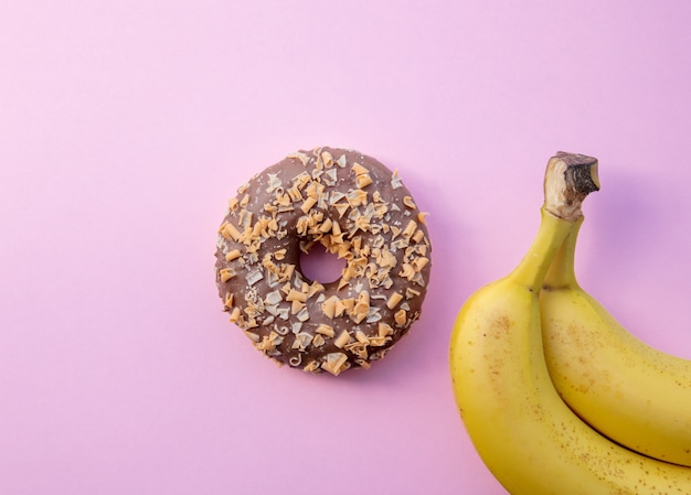 Banana amarela e donut em fundo rosa. acima vista