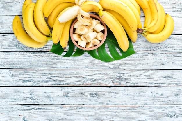 Foto banana com folhas verdes em uma mesa de madeira branca frutas tropicais vista superior espaço para cópia grátis