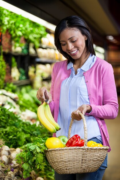 Banana de compra da mulher na seção orgânica