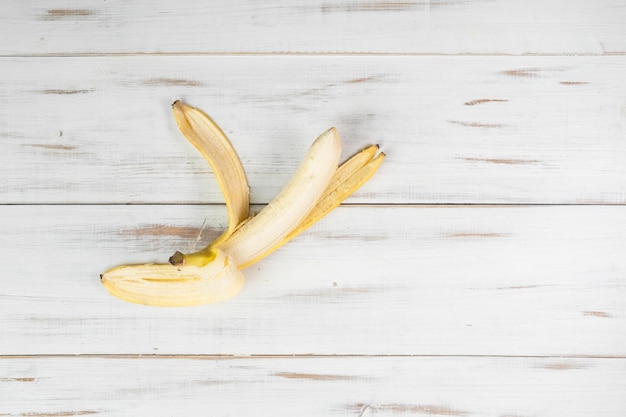 Banana descascada sobre fundo claro de madeira uma banana mordida