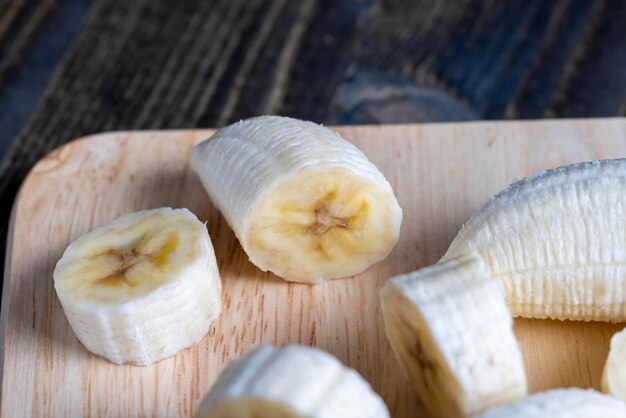 Banana fatiada em uma mesa de madeira enquanto cozinha banana fresca cortada em vários pedaços