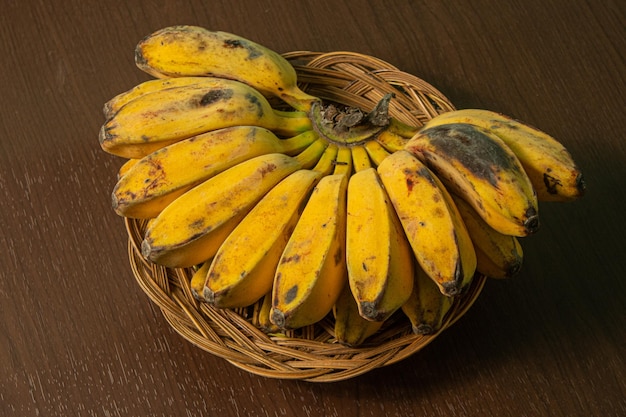 Banana madura amarela em uma placa de vime e fundo de madeira