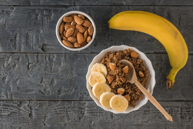 Banana madura, amêndoas e mingau de quinua com cacau em uma mesa de madeira. Dieta saudável. Postura plana.